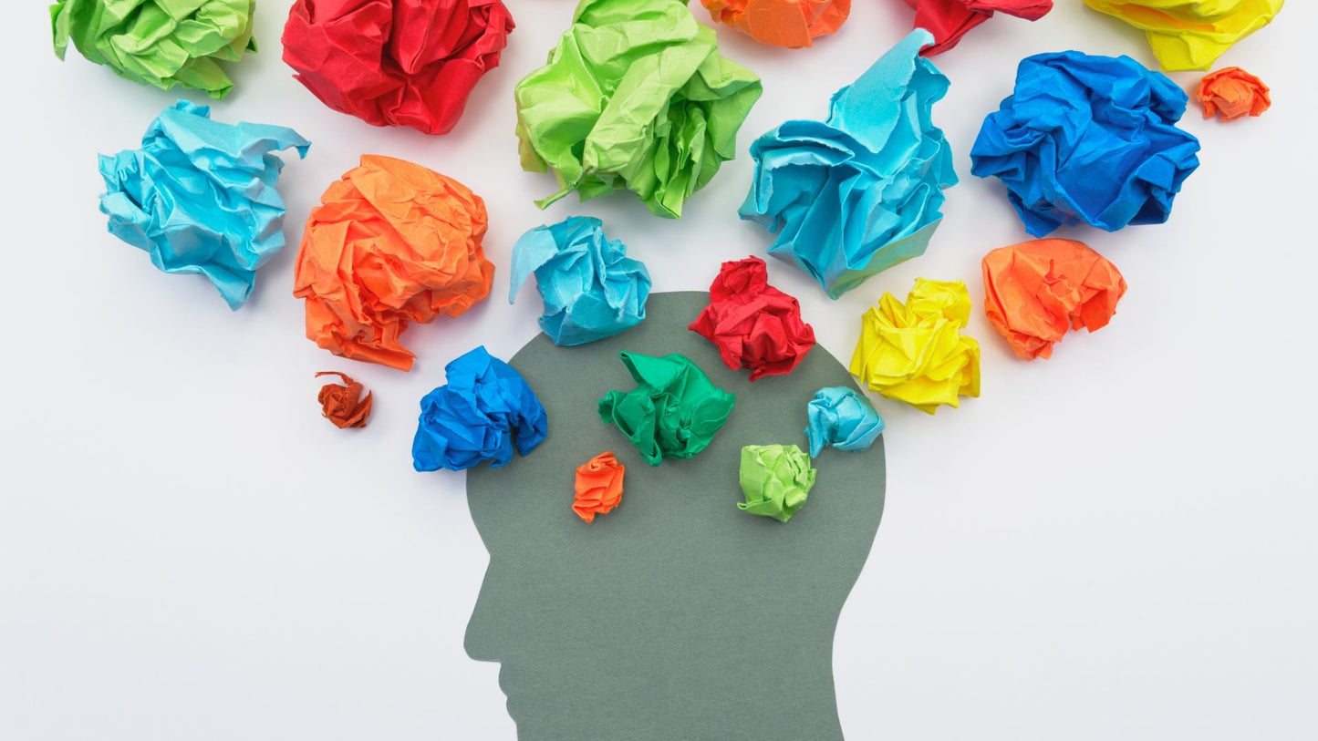 The image depicts a silhouette of a head with colorful crumpled paper balls inside, symbolizing a range of emotions cluttering one's mind, suggesting the need for emotional release.