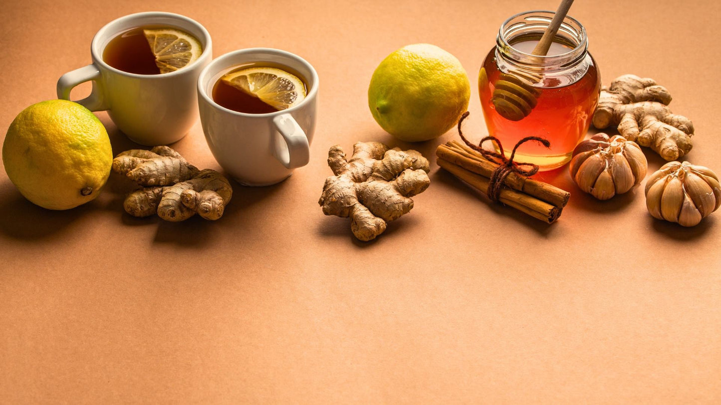 The image shows a natural remedy setup with lemon, ginger, honey in a jar, cinnamon sticks, and whole garlic cloves, suggesting ingredients for a health-related recipe or homeopathic solution.